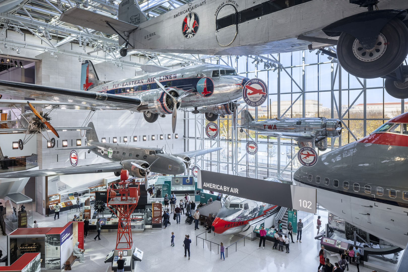Silver airplanes are suspended in the air in an atrium of the Smithsonian's National Air and Space Museum